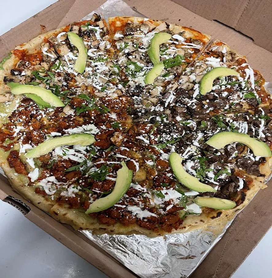 A tlayuda topped with avocado slices and crema in a takeout box