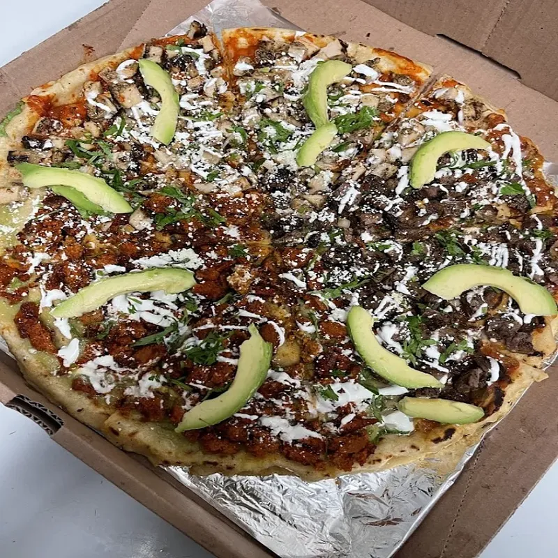A tlayuda topped with avocado slices and crema in a takeout box