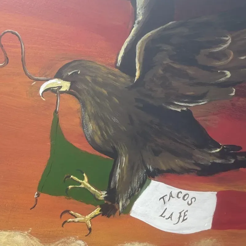 A painted mural of a Mexican eagle holding a snake over the flag, with a banner reading Tacos La Fe